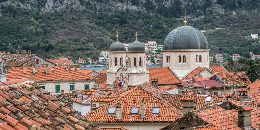 Cityscape with red tiled roofs and mountain back Diva rent a car Montenegro